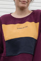 person wearing upcycled sweater, featuring 'no labels, just vibes.' embroidered on the front, repurposed in canada