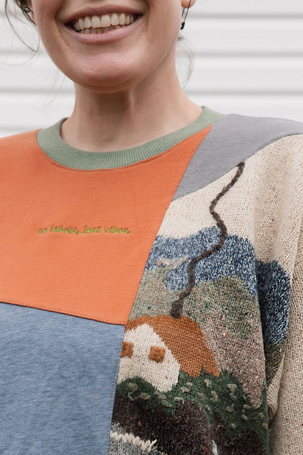 person wearing a one-of-a-kind patchwork sweater, featuring a knit cottage motif, upcycled in canada, detail shot featuring no labels, just vibes embroidery
