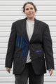 Person wearing a dark gray blazer with denim patch and visible embroidery, upcycled in canada