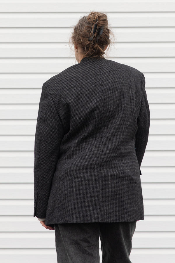 Person wearing a dark gray blazer with denim patch and visible embroidery, upcycled in canada