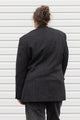 Person wearing a dark gray blazer with denim patch and visible embroidery, upcycled in canada