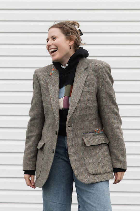 Person wearing a brown blazer with floral embroidery details upcycled in canada