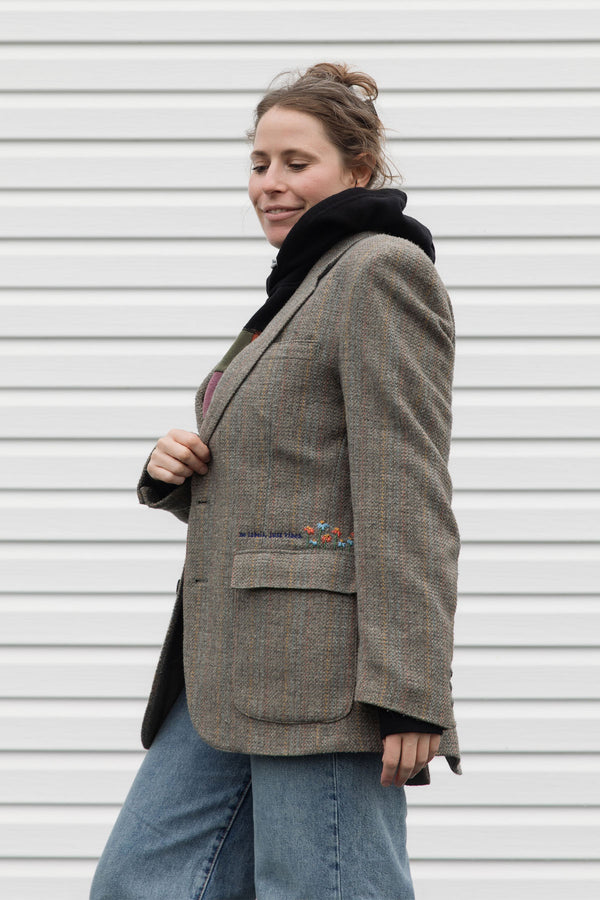 Person wearing a brown blazer with floral embroidery details upcycled in canada