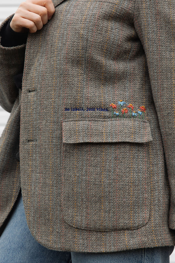 Person wearing a brown blazer with floral embroidery details upcycled in canada