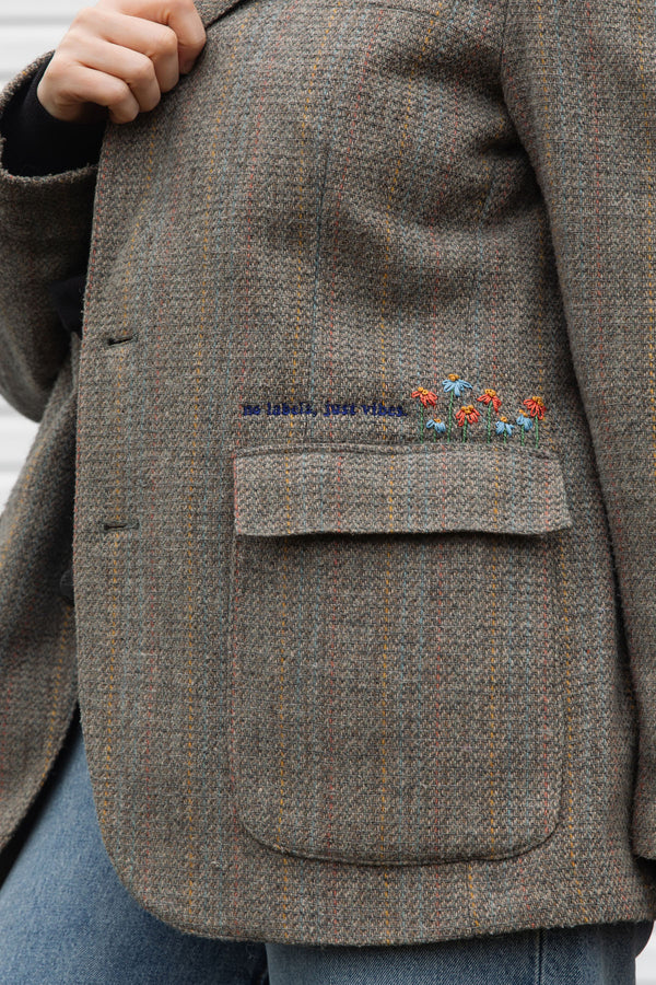 Person wearing a brown blazer with floral embroidery details upcycled in canada