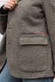 Person wearing a brown blazer with floral embroidery details upcycled in canada