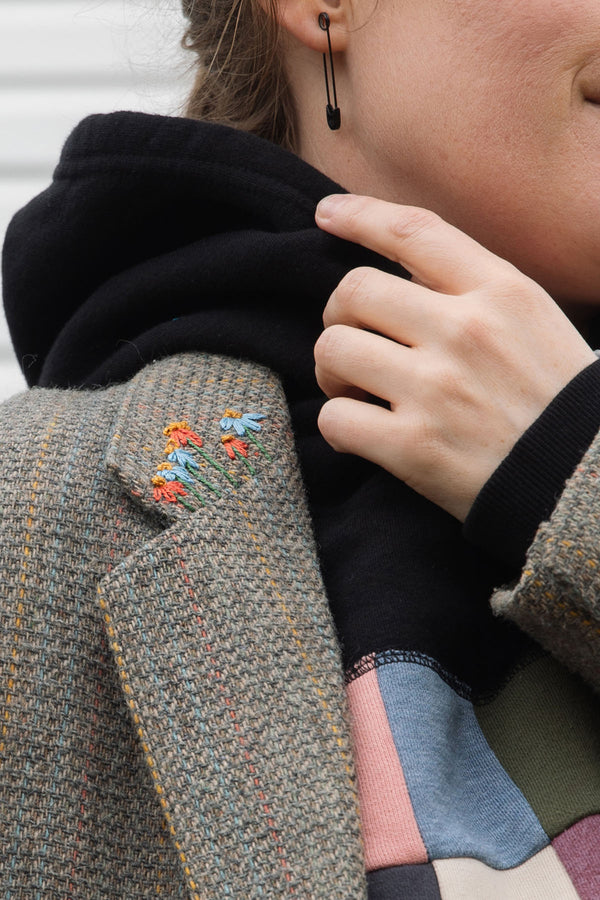Person wearing a brown blazer with floral embroidery details upcycled in canada