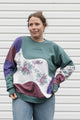 person wearing colourful flower sweater. Purple, Maroon and Green floral motif, upcycled in canada