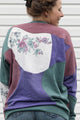 person wearing colourful flower sweater. Purple, Maroon and Green floral motif, upcycled in canada