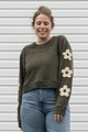 Woman wearing a green sweatshirt with floral designs on sleeves, upcycled in canada