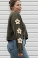Woman wearing a green sweatshirt with floral designs on sleeves, upcycled in canada