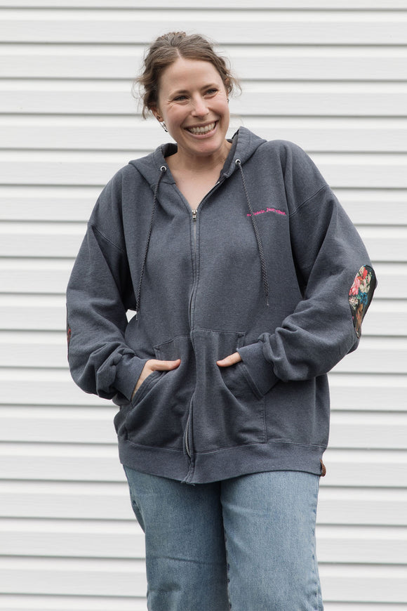 person wearing grey zip up hoodie with floral elbow patches