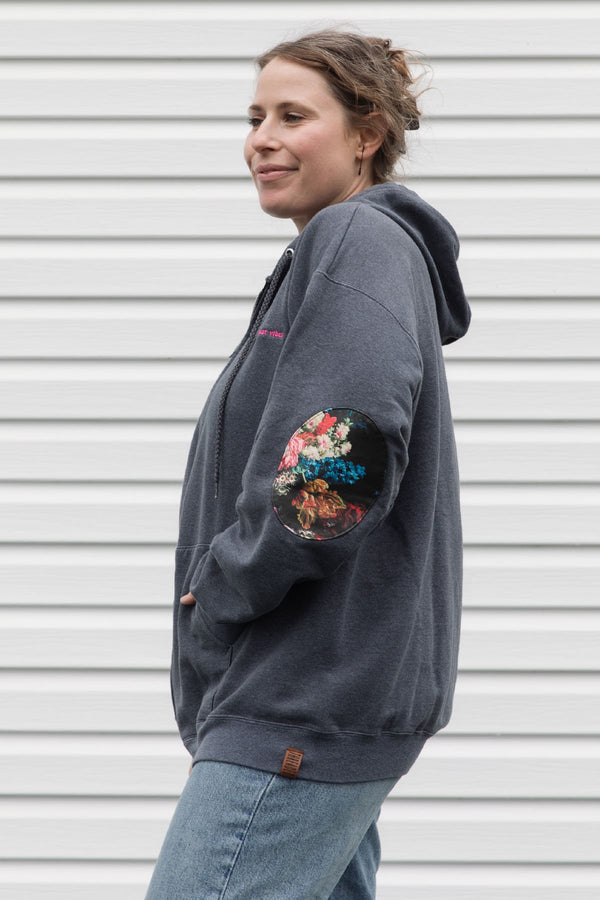 person wearing grey zip up hoodie with floral elbow patches