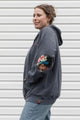 person wearing grey zip up hoodie with floral elbow patches