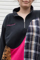 person wearing black half zip with lots of colour details and patterns, upcycled in canada detail shot of 'no labels, just vibes.' embroidery