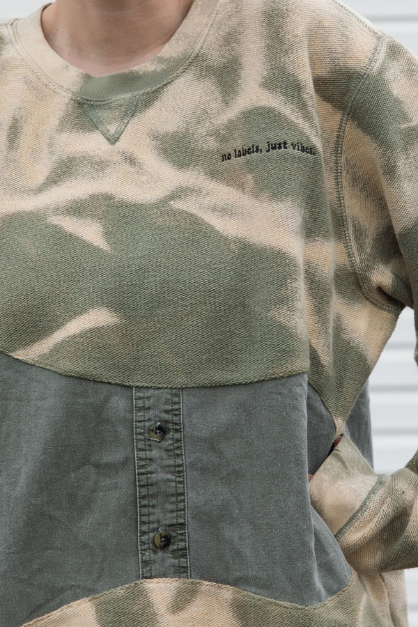 person wearing an unique upcycled pullover, repurposed in canada, detail shot of 'no labels, just vibes.' embroidery