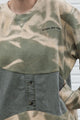 person wearing an unique upcycled pullover, repurposed in canada, detail shot of 'no labels, just vibes.' embroidery