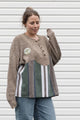 person wearing oversized brown knit with striped bottom, upcycled in canada