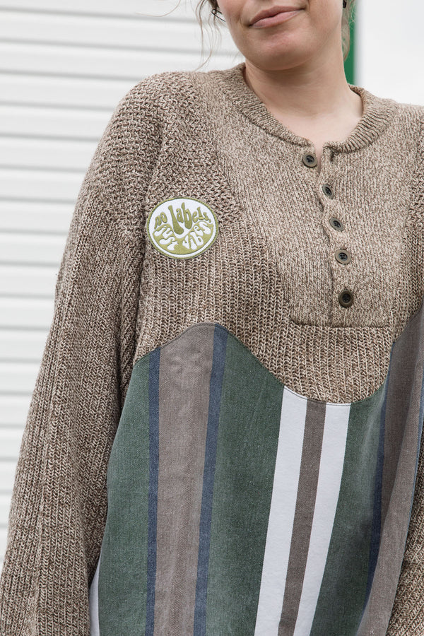 person wearing oversized brown knit with striped bottom, upcycled in canada, detail shot of 'no labels, just vibes.' patch