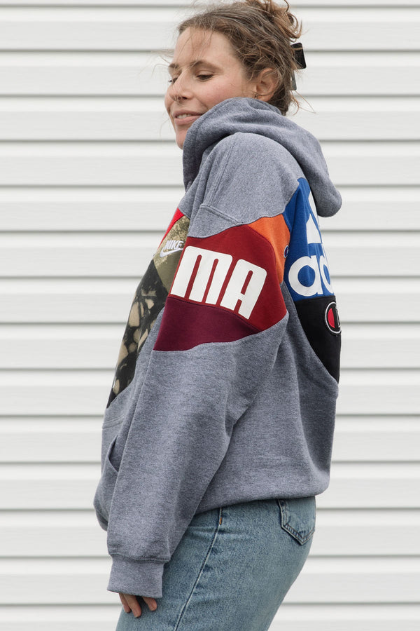 Person wearing a gray hoodie with colorful brand logos, upcycled in canada
