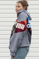 Person wearing a gray hoodie with colorful brand logos, upcycled in canada