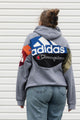 Person wearing a gray hoodie with colorful brand logos, upcycled in canada