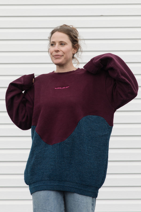 Person wearing a two-tone sweater with maroon and blue sections upcycled in canada