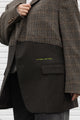 tweed blazer wtih green bottom, raw edges, upcycled in canada, detail shot of 'no labels, just vibes.' embroidery