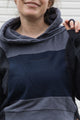 person is wearing a two tone navy hoodie, upcycled in canada, detail shot of 'no labels, just vibes.' embroidery
