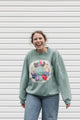 person wearing a mint green sweater with quilted pinwheel on the front, upcycled in canada