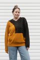 Person wearing a two-tone sweater with mustard yellow and black, upcycled in canada
