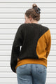Person wearing a two-tone sweater with mustard yellow and black, upcycled in canada