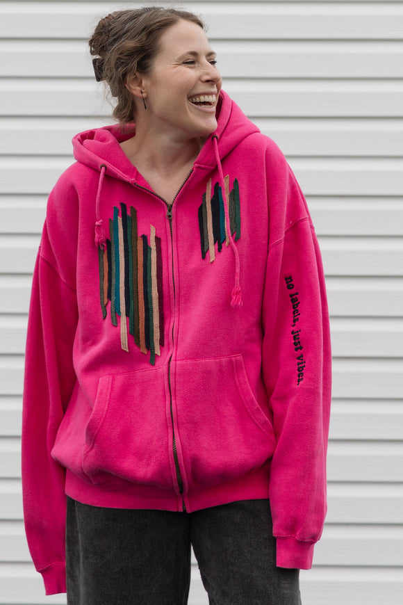 Person wearing a bright pink hoodie with a unique and colourful design, upcycled in canada