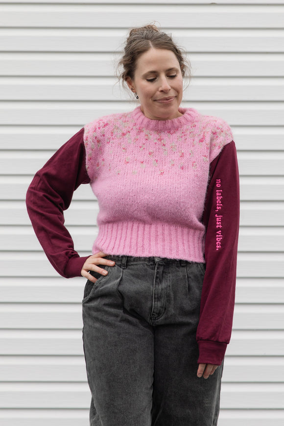 person wearing a pink knit sweater with burgundy sleeves, upcycled in canada
