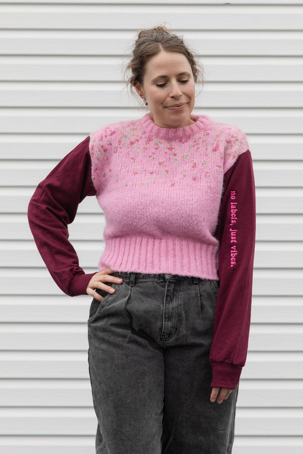 person wearing a pink knit sweater with burgundy sleeves, upcycled in canada