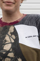 Woman wearing a colorful patterned patchwork sweater upcycled in canada, detail shot of 'no labels, just vibes.' embroidery
