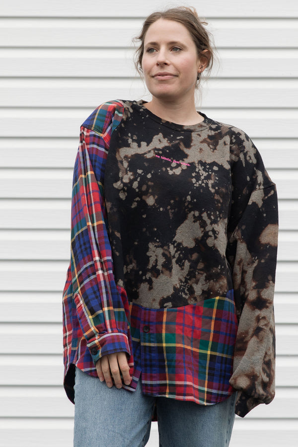 person wearing bleached sweater that is sewn together with red plaid shirt, upcycled in canada
