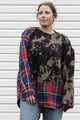 person wearing bleached sweater that is sewn together with red plaid shirt, upcycled in canada