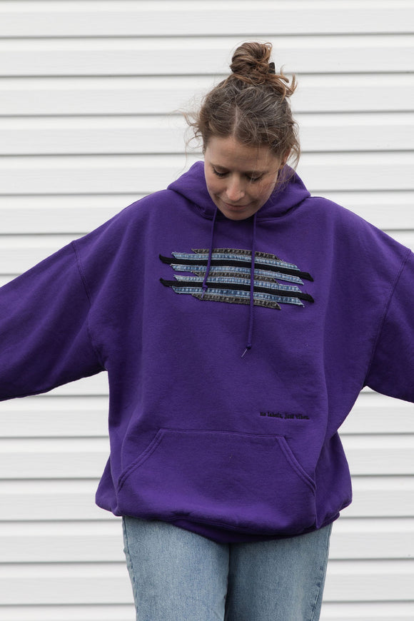 Person wearing a purple hoodie with a graphic design featuring denim seams, upcycled in canada