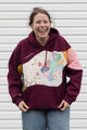 Person wearing a maroon hoodie with a colorful abstract design made with quilting scraps, upcycled in canada