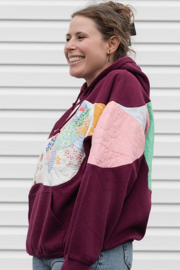 Person wearing a maroon hoodie with a colorful abstract design made with quilting scraps, upcycled in canada