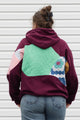 Person wearing a maroon hoodie with a colorful abstract design made with quilting scraps, upcycled in canada