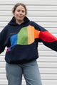 Person wearing a navy hoodie with a colourful rainbow design upcycled in canada