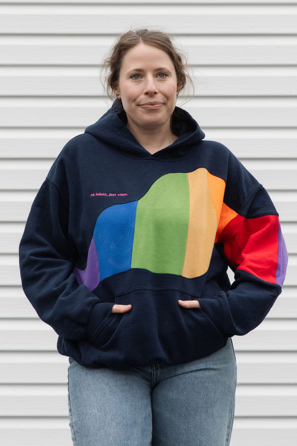 Person wearing a navy hoodie with a colourful rainbow design upcycled in canada