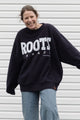 Person wearing a black 'ROOTS Canada' sweatshirt, upcycled in canada