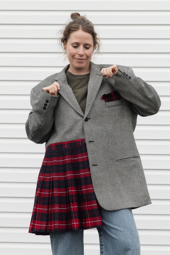 Person wearing a gray blazer sewn together with a red plaid skirt, upcycled in canada