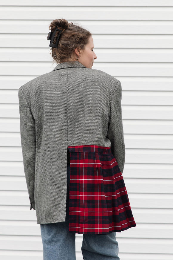 Person wearing a gray blazer sewn together with a red plaid skirt, upcycled in canada