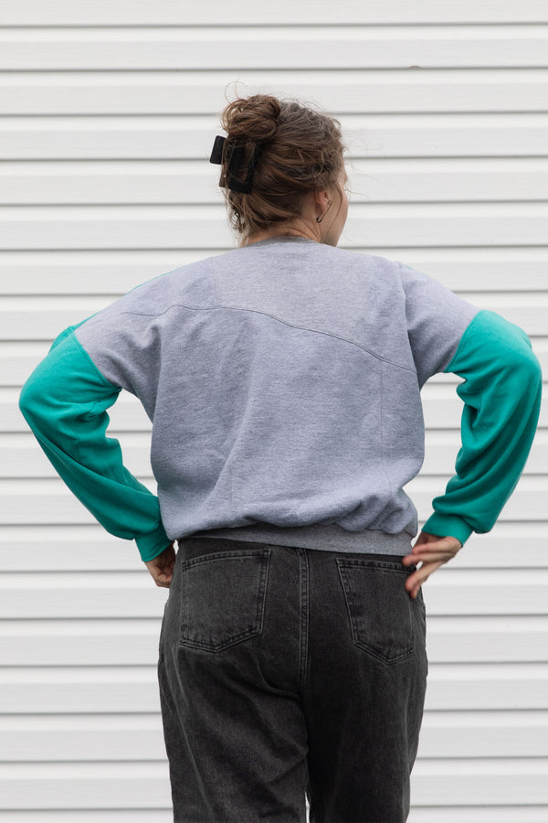 Person wearing a teal, blue and grey vintage sweater, upcycled in canada
