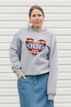 Person wearing a gray sweatshirt with a colorful heart design against a white background