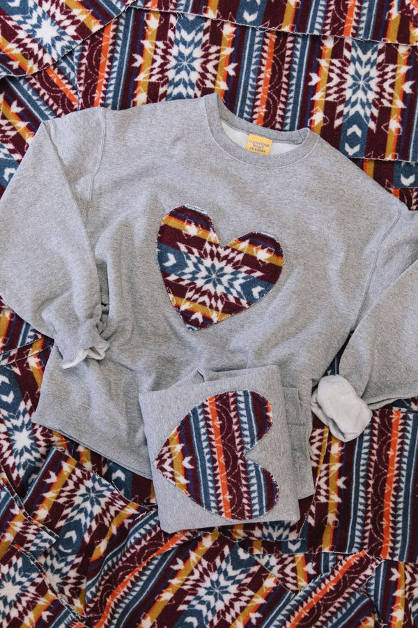 Gray sweatshirt with heart designs on a patterned fabric background